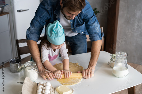 Fotografía Daddy with daughter baking cake together in home kitchen.