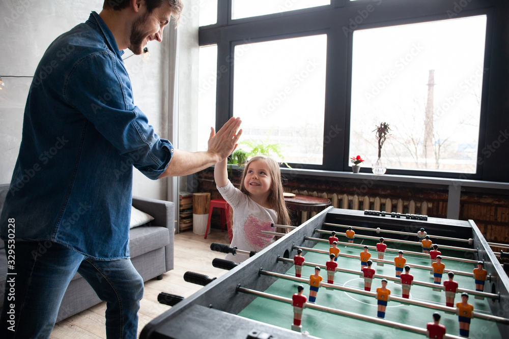 father and daughter playing table football at home - obrazy, fototapety, plakaty 