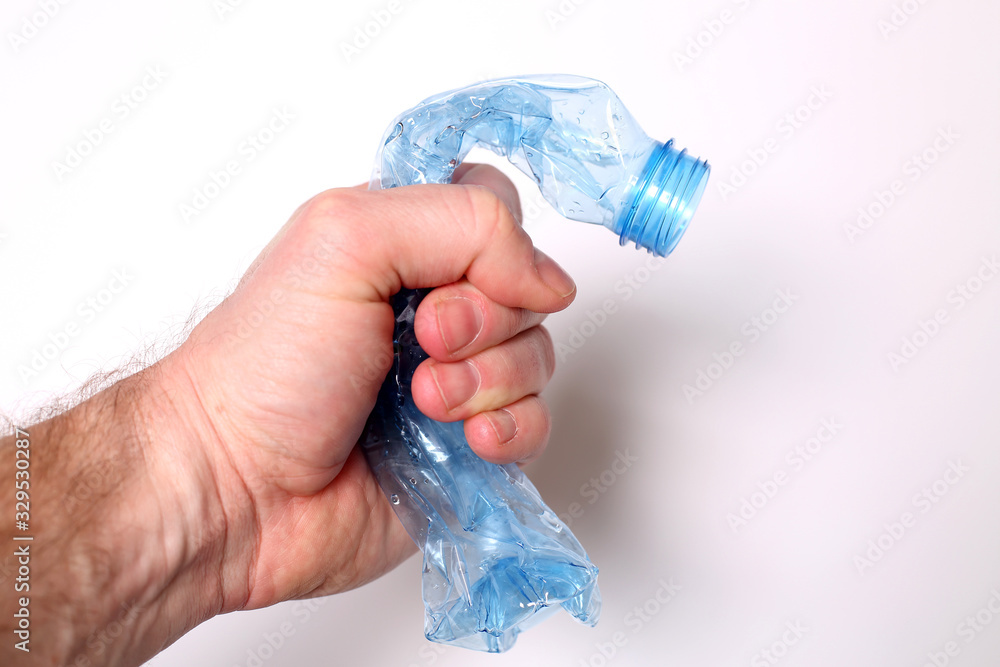 Ręka zgniata plastikową butelkę pet - obrazy, fototapety, plakaty 