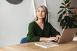 © Drobot Dean - Photo of gray-haired beautiful businesswoman typing on laptop