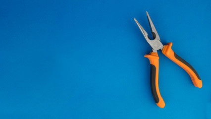 orange pliers lying on a blue background