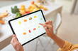 © rh2010 - Woman shopping food online using a digital tablet at the kitchen, close-up view on a tablet screen. Concept of buying online using mobile devices