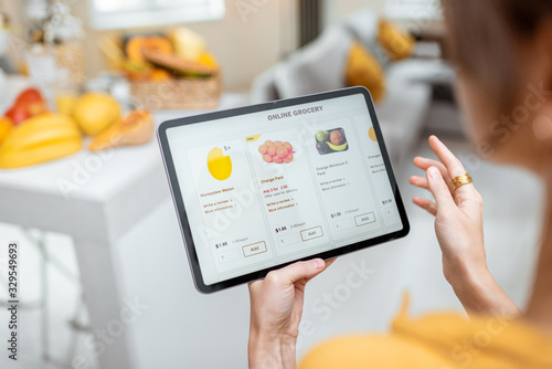 Fotomural Woman shopping food online using a digital tablet at the kitchen, close-up view on a tablet screen