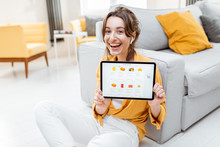 Young And Cheerful Woman Showing A Digital Tablet Screen With Launched Online Store, Shopping Online At Home. Concept Of Buying Online Using Mobile Devices