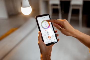 Controlling light bulb temperature and intensity with a smartphone application. Concept of a smart home and managing light with mobile devices