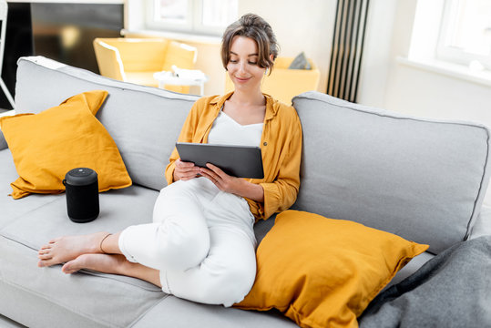 young and cheerful woman using a digital tablet while sitting relaxed on the couch at home. concept 