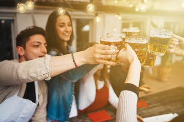 Wall Mural - Group of young people having lunch on a terrace of an apartment at sunset - Millennials having fun together on a day of celebration - Toast with mugs of beer