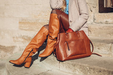 Close Up Of Woman Wearing Stylish Orange Boots Leather Skirt Holding Purse Outdoors. Spring Fashion Accessories Clothes