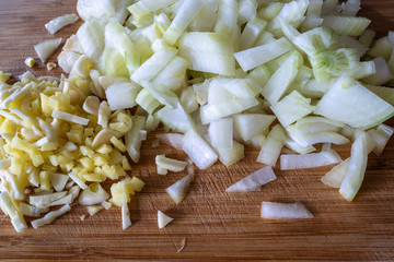 Chopped raw onion and ginger on wooden board - close up