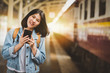 © interstid - happy woman traveler with smartphone at train station platform