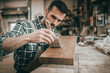 © leszekglasner - Craftsman applies varnish on wooden board by paintbrush in his carpentry workshop