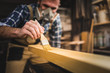 © leszekglasner - Carpenter with mask applies paint using paintbrush in carpentry workshop