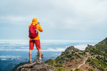 Wall Mural - young adult caucasian man dressed sporty clothes with backpack taking a picture from pico ruivo moun