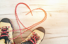 Conceptual Image Of The Pair New Trekking Boots On The Wooden Floor Background With Released Long Shoelaces Behind Lying In Heart Shape.