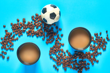 Wall Mural - Full black cardboard glass of coffee near scattered beans and football, soccer ball on blue background. Concept of break, recreation, sport. Top view