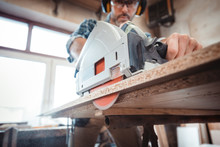 Carpenter Using Professional Circular Saw To Cutting A Wooden Board In Carpentry Workshop