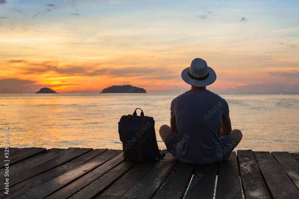 wanderlust travel, tourist with backpack sitting near the sea, man enjoying sunset, solo traveler backpacker in Asia - obrazy, fototapety, plakaty 
