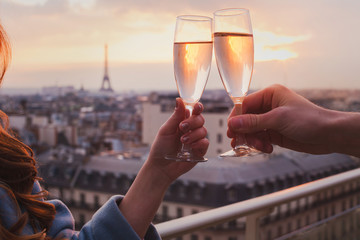 couple drinking champagne or wine in Paris luxurious restaurant with view of Eiffel tower, luxury romantic getaway honeymoon