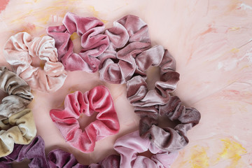 Collection of trendy velvet scrunchies on pink background. Diy accessories and hairstyles concept, copy space