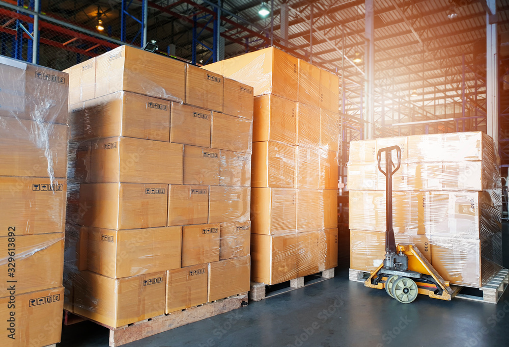 Interior of warehouse, stack package boxes on pallets and hand pallet truck, warehouse industry delivery shipment goods, logistics, transport - obrazy, fototapety, plakaty 
