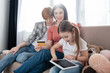 © LIGHTFIELD STUDIOS - Selective focus of kid using digital tablet near mothers with credit card on couch in living room