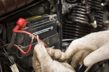 The hands of the mechanic replacing  fuse in motorcycle and selects the correct fuse. selective focus