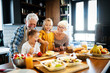 © NDABCREATIVITY - Happy grandchildrens girls having breakfast with her grandparents