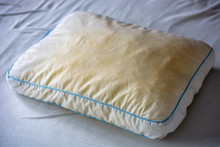 Old Dirty Used Yellow Sweat Stained Pillow On A Mattress. Condition Of The Pillow Used For A Long Time.