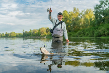 Wall Mural - Pike fishing. Fisherman catch fish in water at river