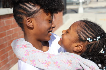 African American Sisters  hugging showing affection looking at each other