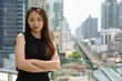 © Ranta Images - Young beautiful Asian businesswoman with arms crossed against view of the city