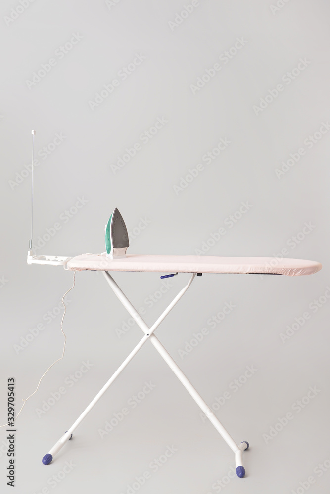 Electric iron and board on grey background