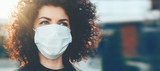 Fototapeta  - Lovely curly haired caucasian lady protecting herself from viruses while wearing special mask