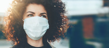 Lovely Curly Haired Caucasian Lady Protecting Herself From Viruses While Wearing Special Mask
