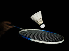 Badminton Racket Impacting Badminton Ball Or Shuttlecock In The Black Scene. It Looks Like A Ball Drops Or Drop Shot. Badminton Playing Concepts, Playing Techniques. There Is Space For A Copy Space.