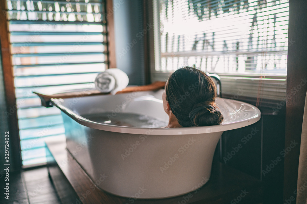 Bath taking woman relaxing in bathtub of hotel room at luxury overwater bungalow resort in Bora Bora, Tahiti. - obrazy, fototapety, plakaty 
