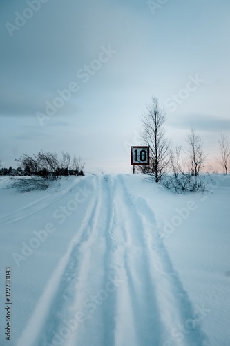 Fotografía Vertical shot of a speed limit sign on the road covered with snow