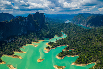 Wall Mural - Aerial drone view looking down onto tiny, jungle covered islands in a huge lake surrounded by limestone cliffs. (Cheow Lan Lake, Khao Sok)