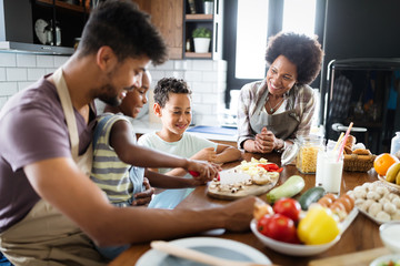 Wall Mural - happy family in the kitchen having fun and cooking together. healthy food at home.