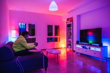 Young Spanish Man Plays Videogames In A Colorful Room While Protecting To Coronavirus COVID-19 Due To Hysteria And Panic Caused By Media And Governments A Very Contagious 