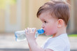 © johnalexandr - handsome boy drinks clear water from a bottle on a sunny day outside