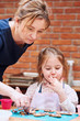 © Przemek Klos - Little girl with her mom's help decorating baked cookies with colorful sprinkle and icing sugar. Kid taking part in baking workshop. Baking classes for children, aspiring little chefs