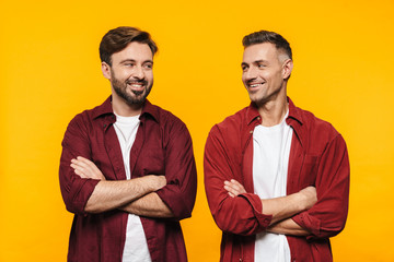 Wall Mural - Image of two handsome men smiling and standing with arms crossed