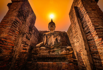 Wall Mural - Big Buddha at sunset in Wat Mahathat temple, Sukhothai Historical Park, Thailand.