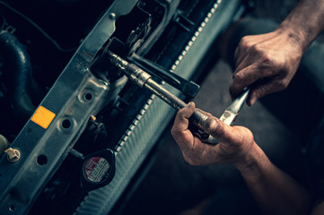 Hands of mechanic working in auto repair shop; check the car radiator