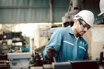 Wall Mural - Professional engineer maintenance industrial in factory. Engineer looking of working at industrial machinery setup in factory. The engineering looks stern about the machine settings in the factory.