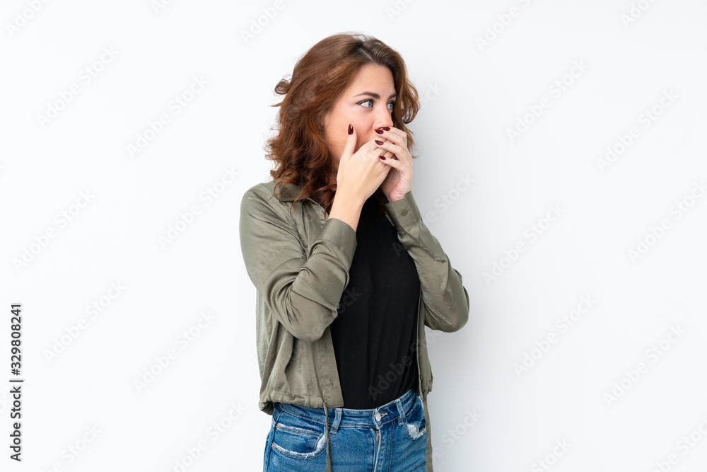 Young Russian woman over isolated white background covering mouth and looking to the side