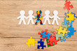 © LIGHTFIELD STUDIOS - Top view of special kid with autism among another and pieces of bright colorful puzzle on wooden background