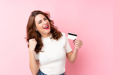 Young Russian Woman Over Isolated Pink Background Holding A Credit Card