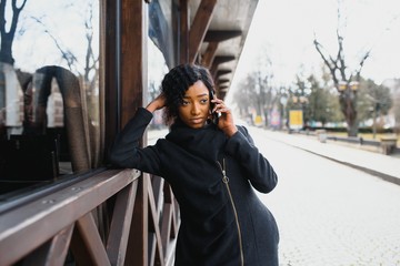 cheerful african woman using smart phone outdoors